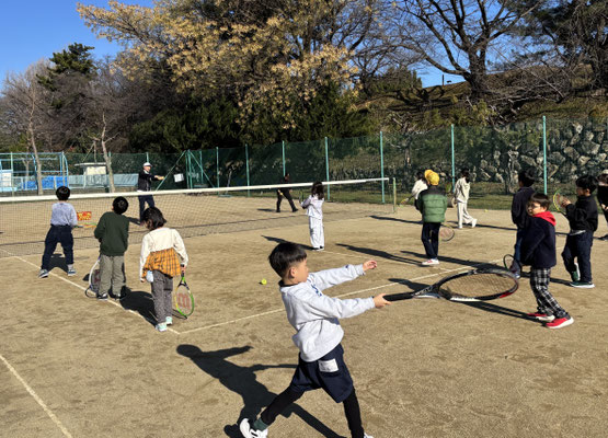 テニスコートでラケットを振る子どもたち
